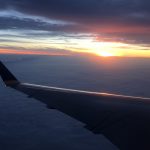 飛行機の翼と雲と太陽の光と海