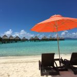 砂浜で傘をさして椅子に座っている