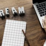 木製テーブルの上に置かれたノートパソコンと携帯電話