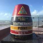 砂浜にある缶飲料、背景はSouthernmost point buoy