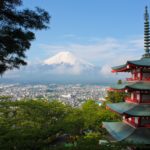 川の隣に立っている時計台、背景は富士山