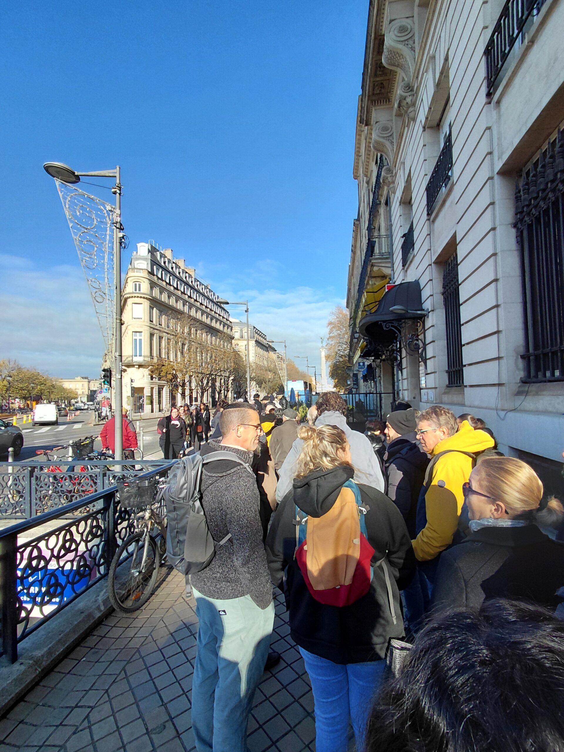 建物の前の歩道を歩いている人たちと観客